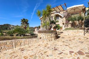 a stone house with palm trees and a stone wall at Corbezzoli in San Teodoro