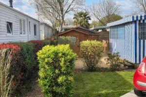 una casa con un cortile con cespugli e una recinzione di Bungalow Charmant à La Baule, Piscine a Saint-André-des-Eaux