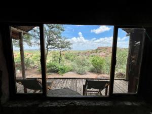 a window with a view of a deck with two chairs at Kaoxa Bush Camp in Linton