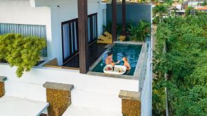 two people in a swimming pool in a house at The Kirana Canggu Hotel in Canggu