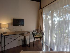 a room with a desk and a window with a television at L'Auberge des Collines in Granges-Les-Beaumont