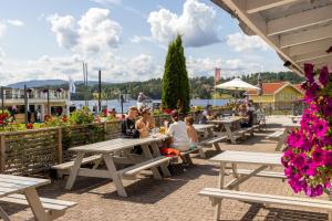 un gruppo di persone seduti ai tavoli da picnic vicino all'acqua di First Camp Norsjø Telemark a Akkerhaugen