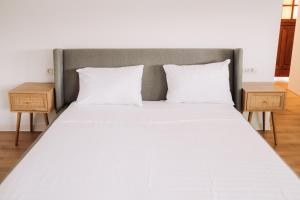 a large bed with white sheets and two night stands at Snagov Forest Villa in Ciolpani