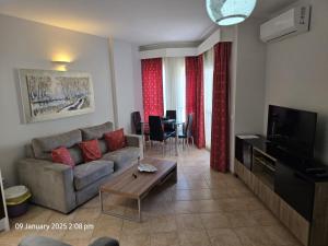 a living room with a couch and a tv and a table at Benal Beach Apartments in Málaga