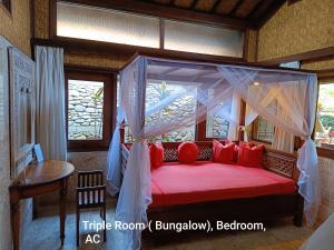 ウブドにあるGuci Guesthousesのベッドルーム1室(天蓋付きベッド1台、赤い枕付)