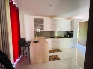 a kitchen with white cabinets and a counter with chairs at King's Horse Villa, Kuruwita in Ratnapura