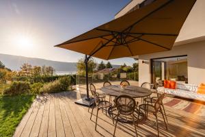 ヴェリエ・デュ・ラックにあるVilla Elegance - Vue Lacのテーブルと椅子と傘のあるパティオ