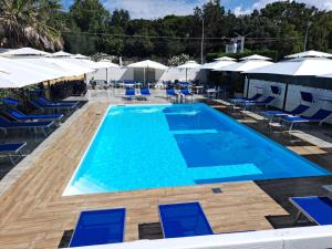 a large swimming pool with blue chairs and umbrellas at Hotel Le Pinede Relax in Licola