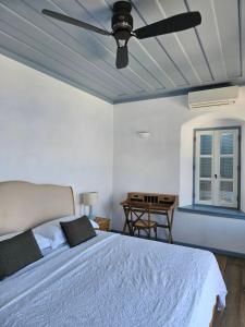 a bedroom with a bed with a ceiling fan at The Anchor House in Symi