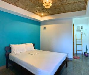 a bed in a room with a blue wall at Tuyom by Hostel 7 in Badian
