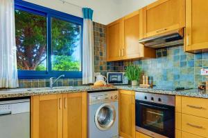 a kitchen with a washing machine and a window at Azzurro Holiday Villas in Peyia