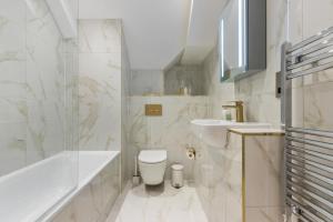 ein weißes Badezimmer mit einer Badewanne, einem WC und einem Waschbecken in der Unterkunft Deluxe 2-Bedroom Saarb Apartment, Leatherhead in Leatherhead + 12 Fotos