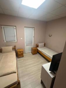 a room with two beds and a flat screen tv at Хотел Елит in Kostinbrod