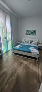 a bedroom with a bed with blue sheets and wood floors at B&b A Due Passi Dal Sole in Porto Empedocle
