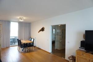 a living room with a dining room table and a television at Kustverhuur, Appartement aan Zee, Port Scaldis 01061 in Breskens