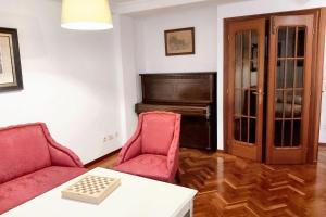 a living room with two red chairs and a piano at Spacious house with terrace and balcony in A Coruña in A Coruña