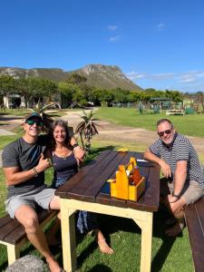 a group of people sitting at a picnic table at Calamari Self Catering in De Kelders