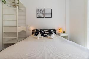a white bedroom with a large bed with black and white pillows at Charming Apartment in the Heart of Málaga in Málaga