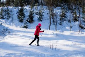 una persona con una chaqueta roja esquiando en la nieve en VISLOW Resort, en Wisła