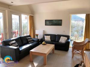 a living room with a black couch and a table at Westduin 6 - Elly Oostdijk Recreatie - Vakantiehuis Vlissingen in Vlissingen