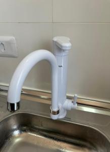 ein weißer Wasserhahn über einem Edelstahlwaschbecken in der Unterkunft Aconchegante Apto Carapicuiba in Carapicuíba + 17 Fotos