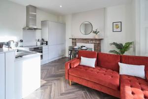 Una sala de estar con un sofá rojo y una cocina. en Host & Stay - Upton House, en Northampton