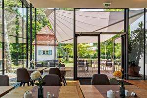 a dining area with tables and chairs and large glass windows at Landhotel Altes Wasserwerk GbR in Freinsheim