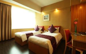 a hotel room with two beds and a desk and a window at The Imperial Hotel in Hong Kong