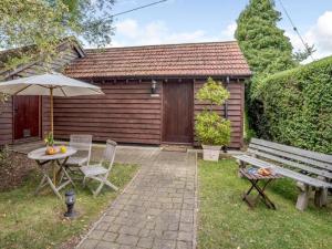 a patio with a bench and a table and an umbrella at Stables Studio in Bedford