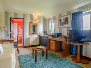 a living room with a tv and a kitchen with a couch at Stables Studio in Bedford
