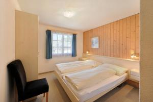 a bedroom with a bed and a chair in it at Apartments Kirchbühl in Grindelwald +32 photos