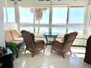 a living room with chairs and a table and windows at Beachfront 75 in Torrox