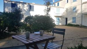 einem Holztisch und einem Stuhl neben einem Gebäude in der Unterkunft Appartement Le Beach31 à 200m de la plage, 1 chambre in La Guérinière