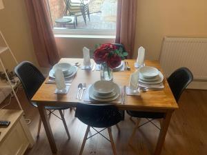 a wooden table with chairs and plates and a vase of flowers at The Napier in Leicester