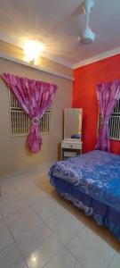 a bedroom with a bed with purple curtains and a mirror at Homestay Hajah Jamilah Sungai Tiram in Ulu Tiram