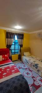 a bedroom with two beds and a window at Homestay Hajah Jamilah Sungai Tiram in Ulu Tiram