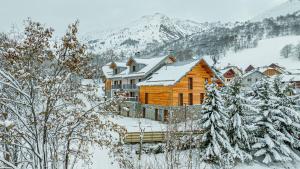 a wooden house in the snow with snow covered trees at Résidence & Spa Les Cîmes d'Auréa in Valloire