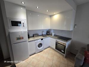 a kitchen with white cabinets and a washer and dryer at Benal Beach Apartments in Málaga