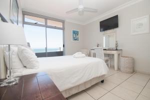 Un dormitorio con una cama y un escritorio con televisión. en 53 Sea Lodge Umhlanga Rocks, en Durban