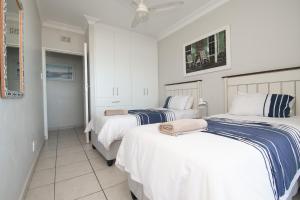 two beds in a room with white and blue sheets at 53 Sea Lodge Umhlanga Rocks in Durban +19 photos