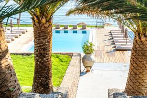 a swimming pool with palm trees and chairs at Hotel Angels in Mythimna