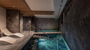 a swimming pool with chairs in a hotel room at Résidence & Spa Les Cîmes d'Auréa in Valloire
