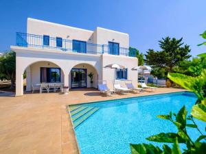 a villa with a swimming pool in front of a house at Azzurro Holiday Villas in Peyia