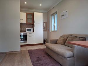 a living room with a couch and a kitchen at BaobabSuites in Johannesburg