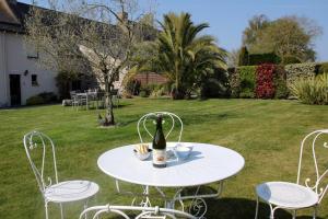 a white table with a bottle of wine and chairs at Le Petit Porcon in Saint-Méloir-des-Ondes