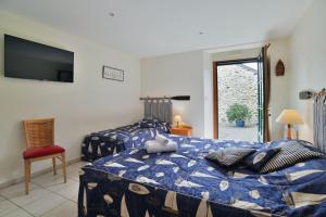 a bedroom with two beds and a tv on the wall at Le Petit Porcon in Saint-Méloir-des-Ondes