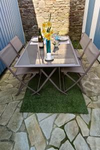 a table with two chairs and a vase with flowers at Le petit chalet bleu in Cancale +2 photos