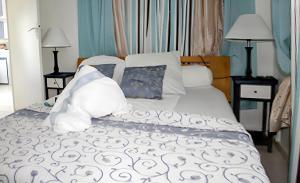 a bed with white sheets and pillows at Bungalow charmant à Sainte-Rose avec terrasse et piscine in Sainte-Rose