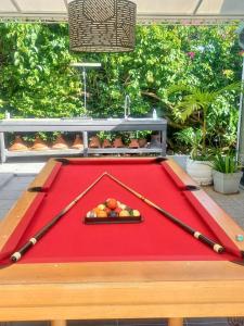 a pool table with two baseball bats and fruit on it at Bungalow charmant à Sainte-Rose avec piscine partagée in Sainte-Rose