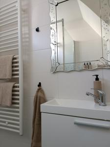 a white bathroom with a sink and a mirror at Cottage at Sea in Noordwijk aan Zee +8 photos